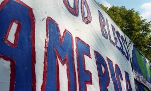 Color photograph showing a decorated bedsheet with the phrase "God Bless America." wall.
