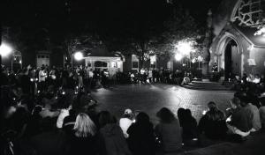 Black and white photograph showing students who are holding candles sitting around the edges of the Quadrangle.