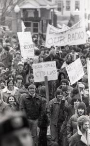 Black and white photograph showing students protesting in the rain, holding signs saying things like "Disco Sucks. GTB Lives" and "Don't Kill Our Radio."
