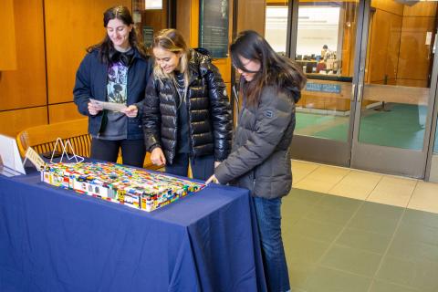 Three people looking at the completed lego ramp set on top of a table in Lauinger Library