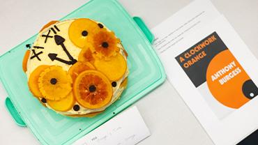 A cake tribute to A Clockwork Orange depicting a clock's hands surrounded by orange slices.