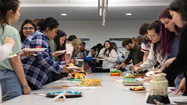 Students crowd around the submissions, cutting pieces from each.