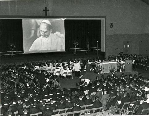 Georgetown students and faculty watching Pope Paul VI's message of congratulations for the 175th Anniversary on an enlarged screen in McDonough Gym. 