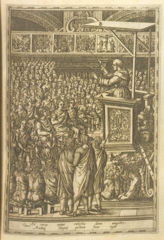 A preacher in a pulpit points to a series of images depicting the life of Christ in front of an Indian crowd.