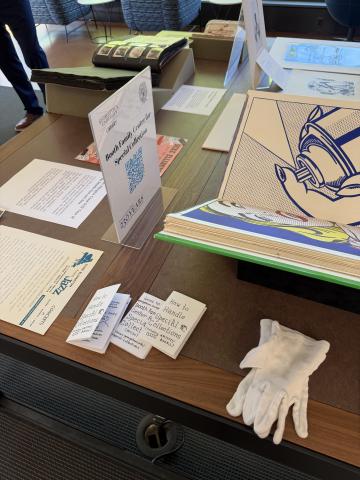 Table filled with artists’ books, rare books, and art collections, with the zines prominently displayed and available for individuals to take.