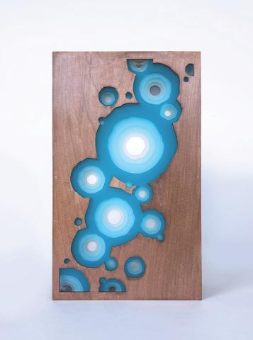 Image of artwork with layers of white, light blue, dark blue, and wood grain