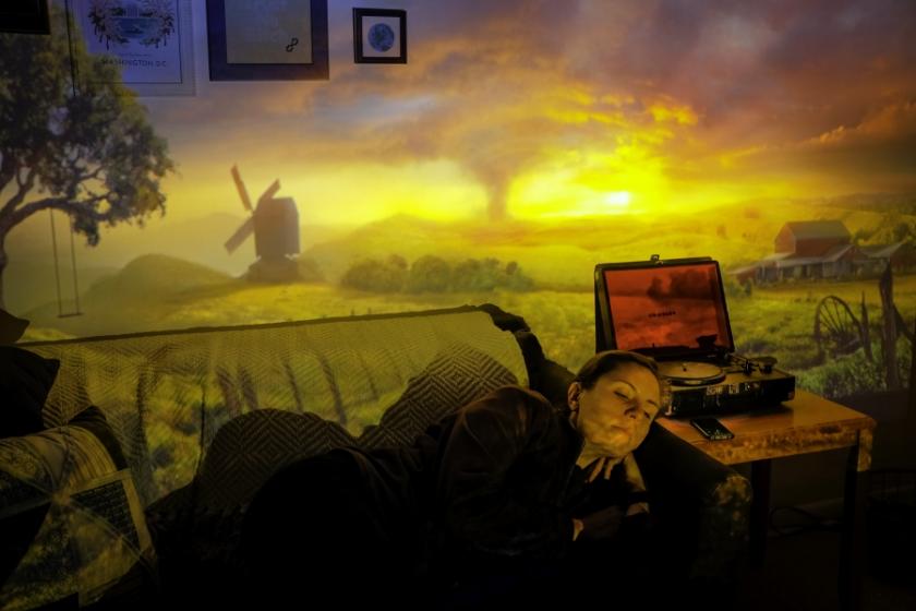 Reclining woman in a room with a projection of a landscape image over her