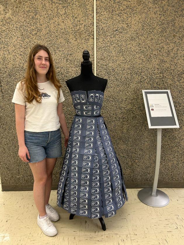 the maker standing next to her dress made from coffee sleeves