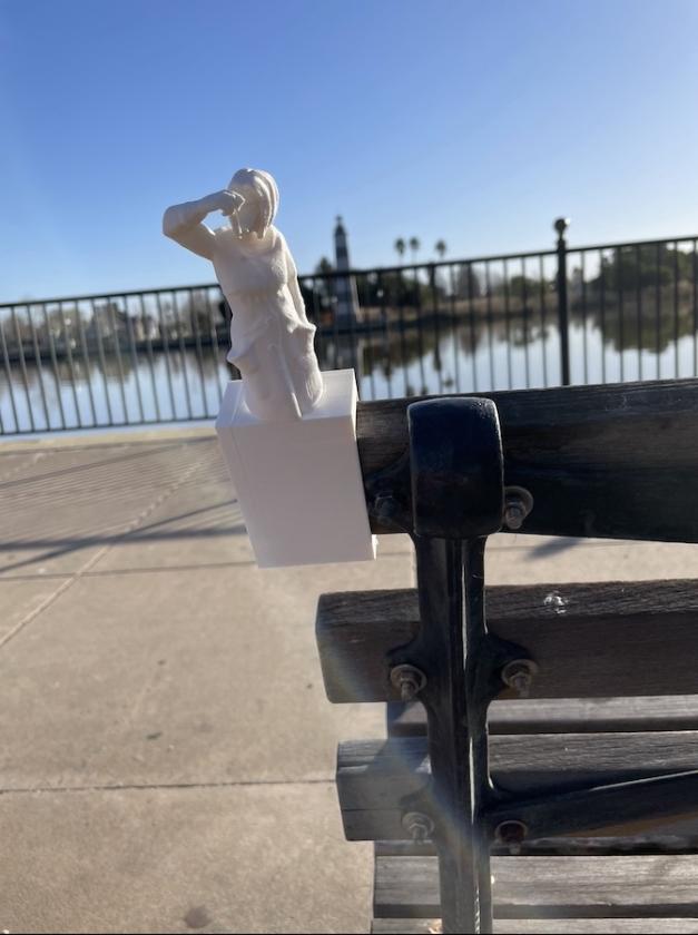 image of 3d printed nurse holding a vaccine vial, mounted on a park bench