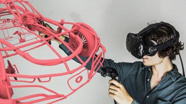 a student in VR goggles manipulating a floating model of a car