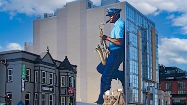 Large mural of a black man wearing a post office uniform playing a saxaphone