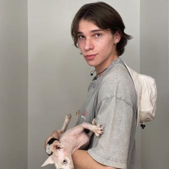 man in a gray shift holding a hairless cat