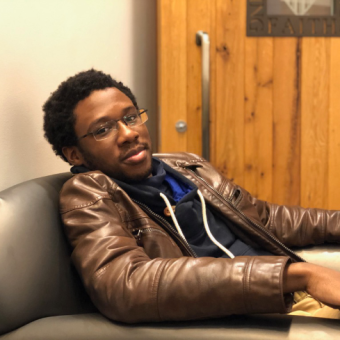 black man with short hair lounges in a chair