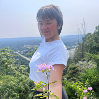 woman in a white shirt holding a wildflower