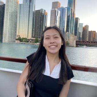 woman smiles standing in front of a city skyline