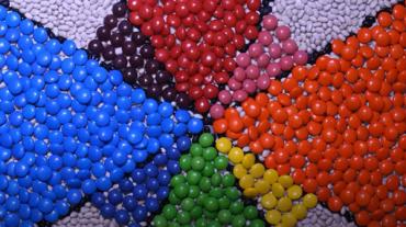 Various colored jelly beans forming triangles in a animation. 