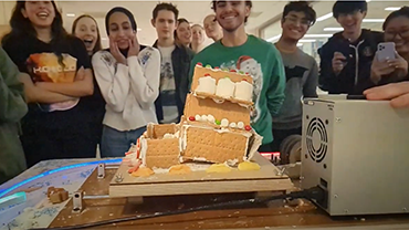 Students watching a gingerbread house falling apart as it's being shaken