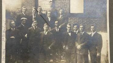 Black and white photograph of fifteen young men in suits and ties.