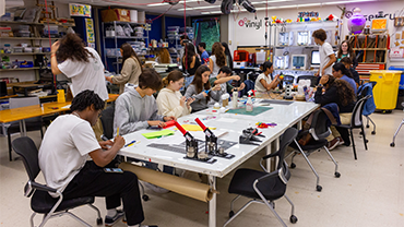 several students sitting around a table making buttons