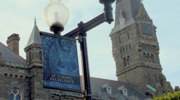 The Healy Hall clock tower and a lampost with a banner that reads Academic Excellence