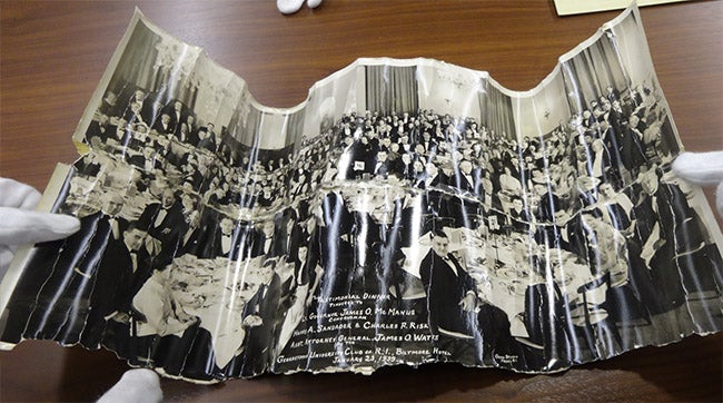 torn and creased photograph of a large group of Georgetown University alumni sitting at tables in a banquet hall