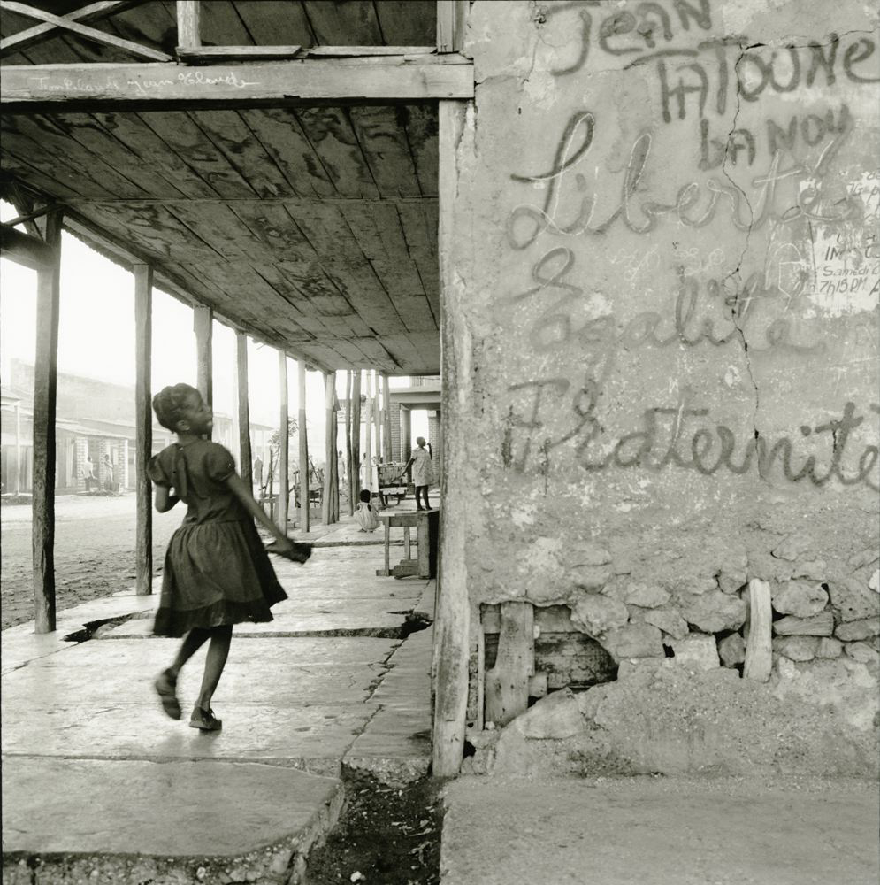 Girl skipping next to wall with the written text Liberte, Egalite, Fraternite