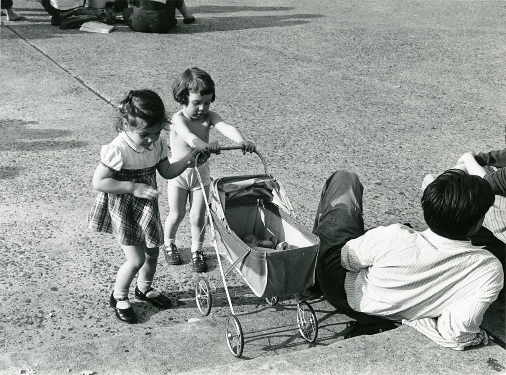 Two you girls pushing a miniature baby carriage