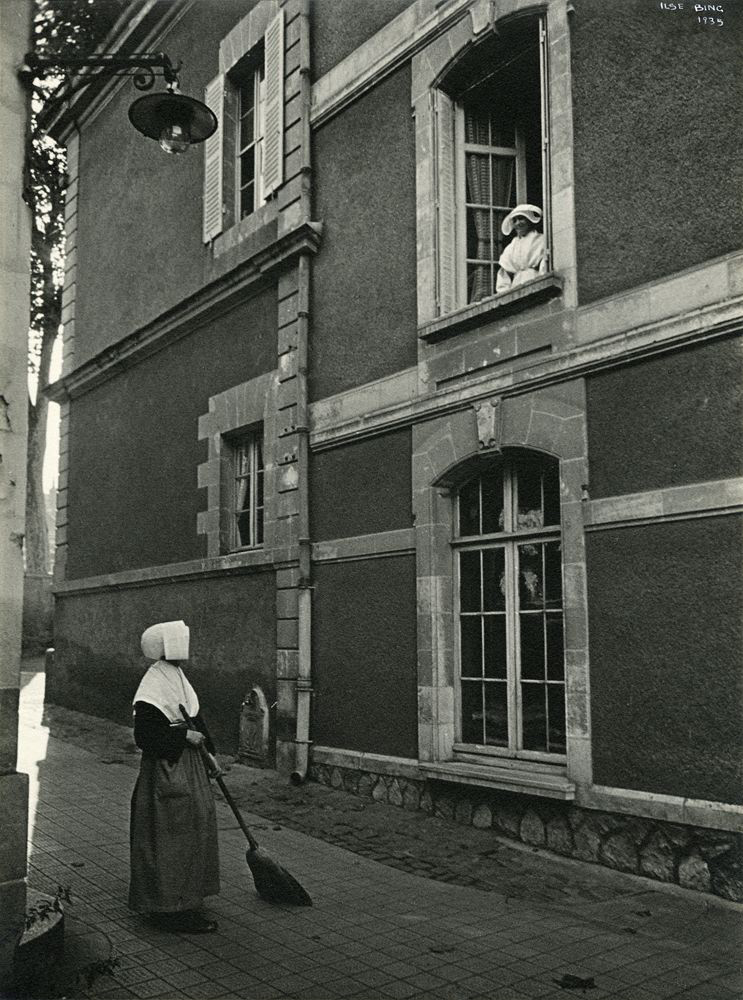 Nun from a window watching a nun sweep