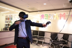 A student in the Library's Idea Lab wears a virtual reality headset while operating the controllers with his hands outstretched