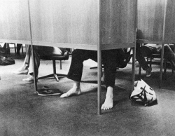 Students seated and studying at carrels in Lauinger Library, with only their feet visible, and one student has removed their shoes and is barefoot